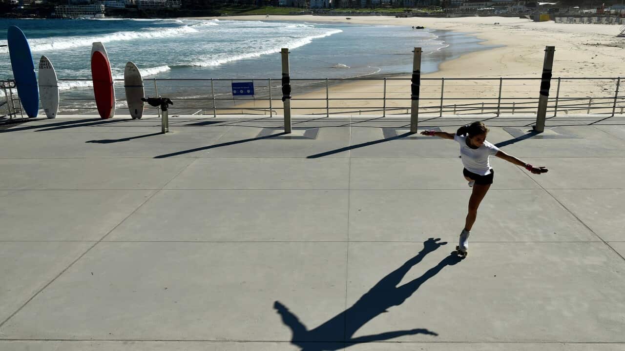 A woman roller skates in front of a closed Bondi Beach in Sydney, Sunday, April 12, 2020. (AAP Image/Joel Carrett) NO ARCHIVING