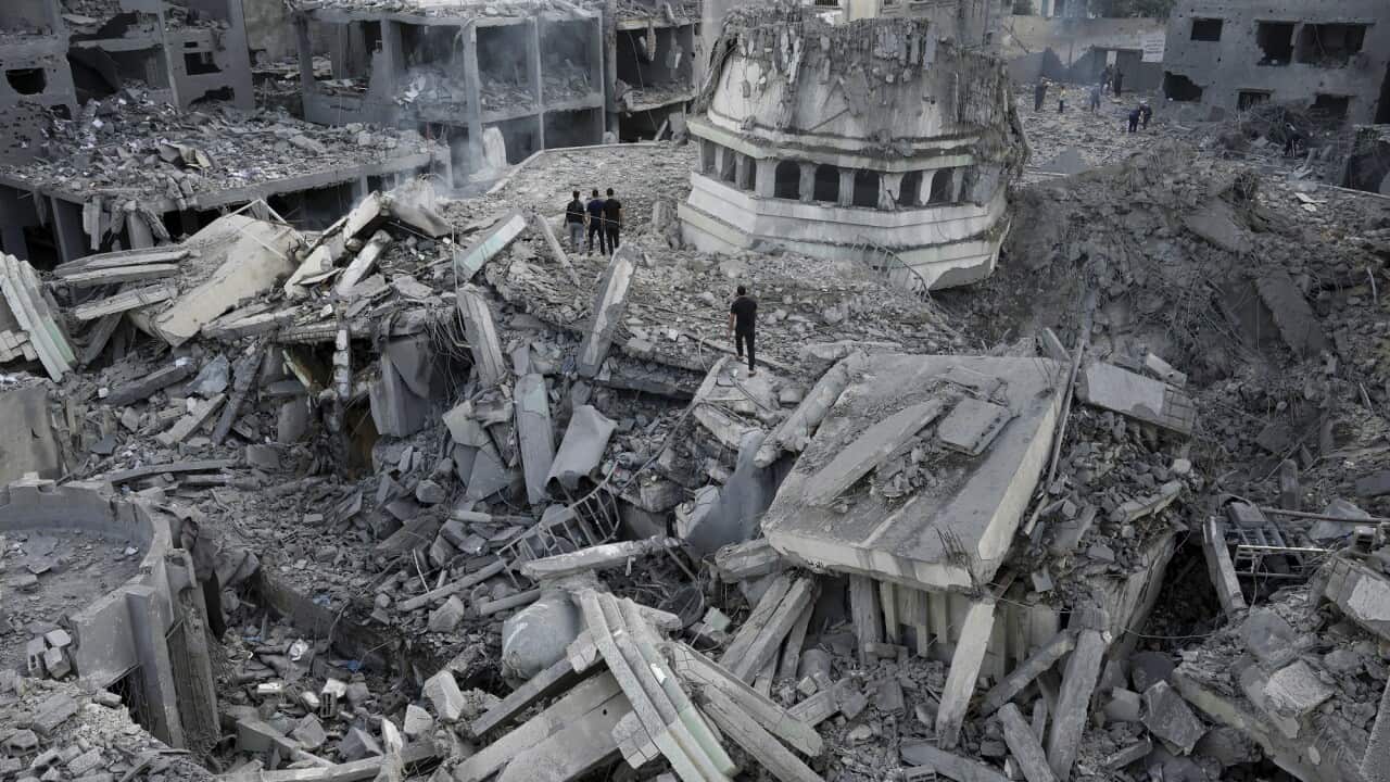 People stand in the ruins of damaged buildings