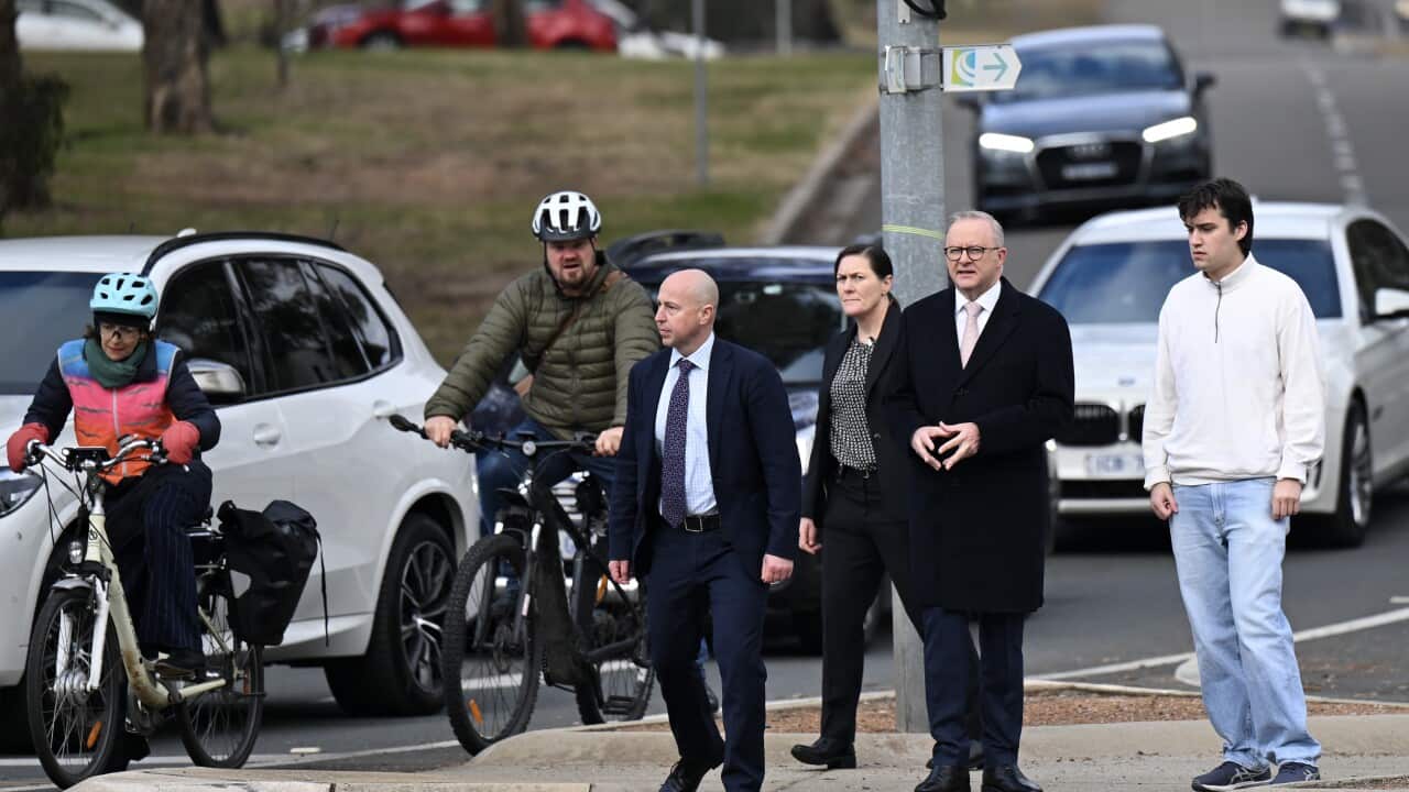 Australian Prime Minister Anthony Albanese and his son Nathan wait at a traffic light as they walk towards Parliament House in Canberra
