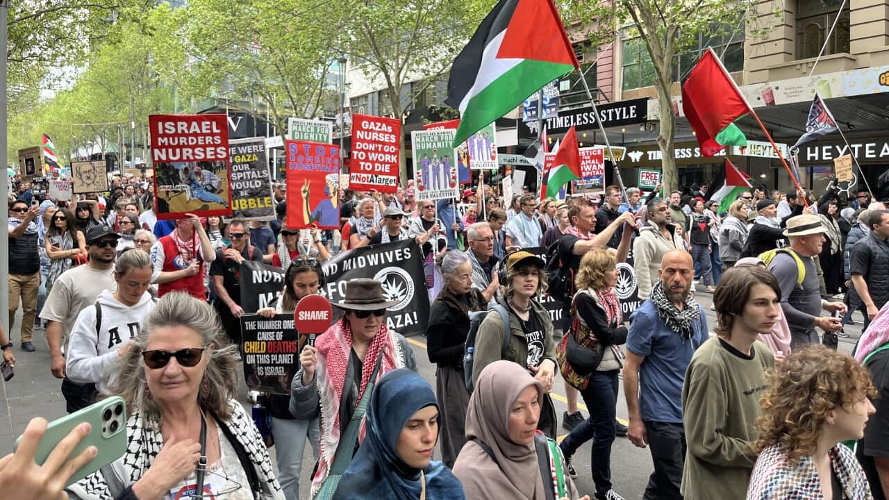 Protesters carrying placards and Palestinian flags marching through Melbourne's CBD.