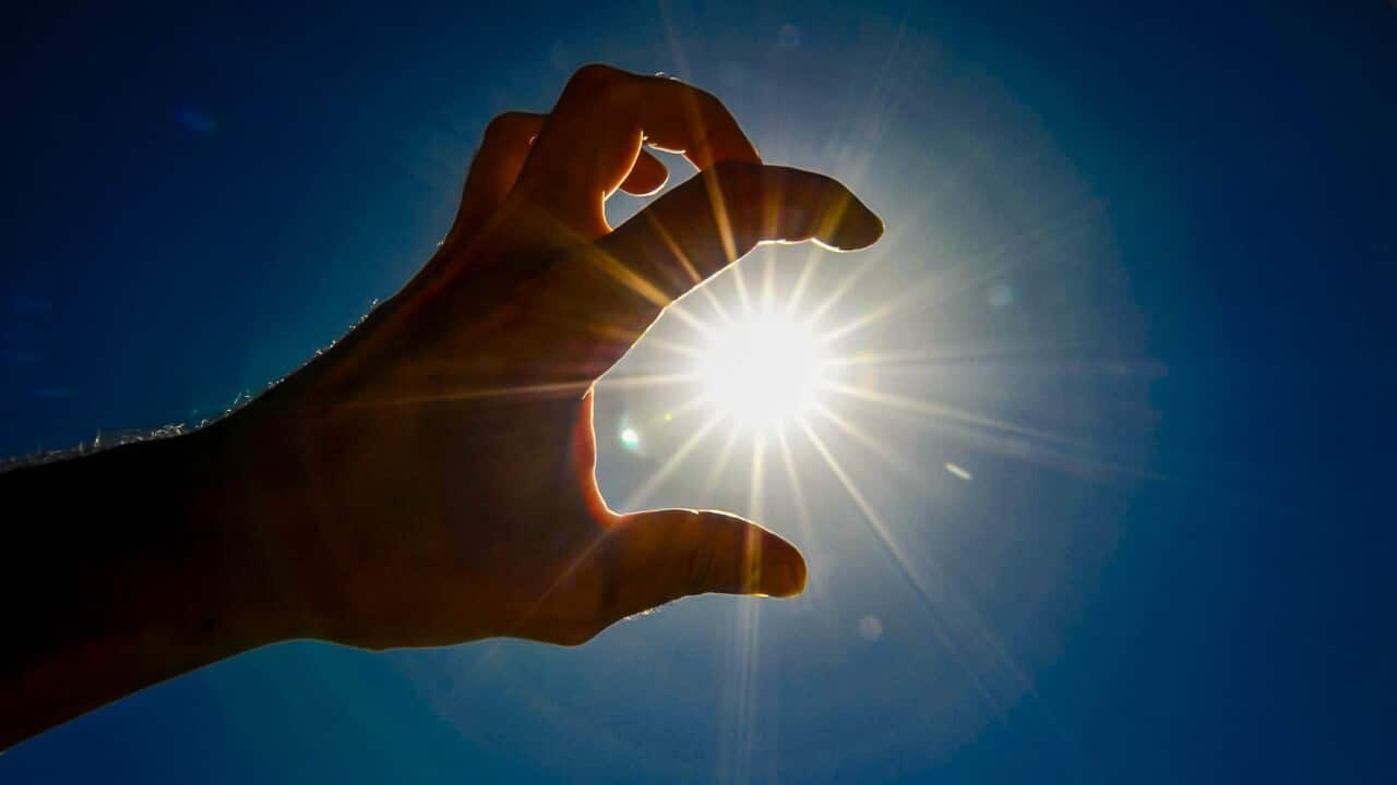 A hand is holding a sun in the sky