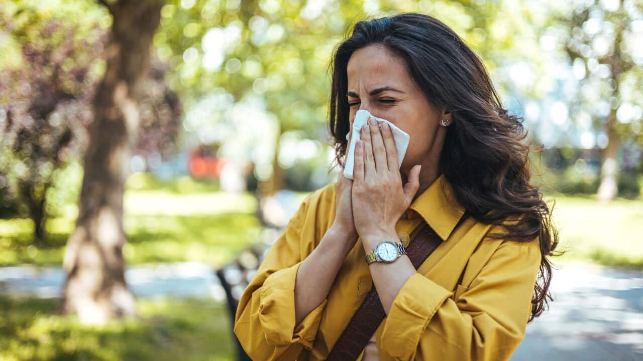 Portrait of female in yellow top with napkin blowing her nose