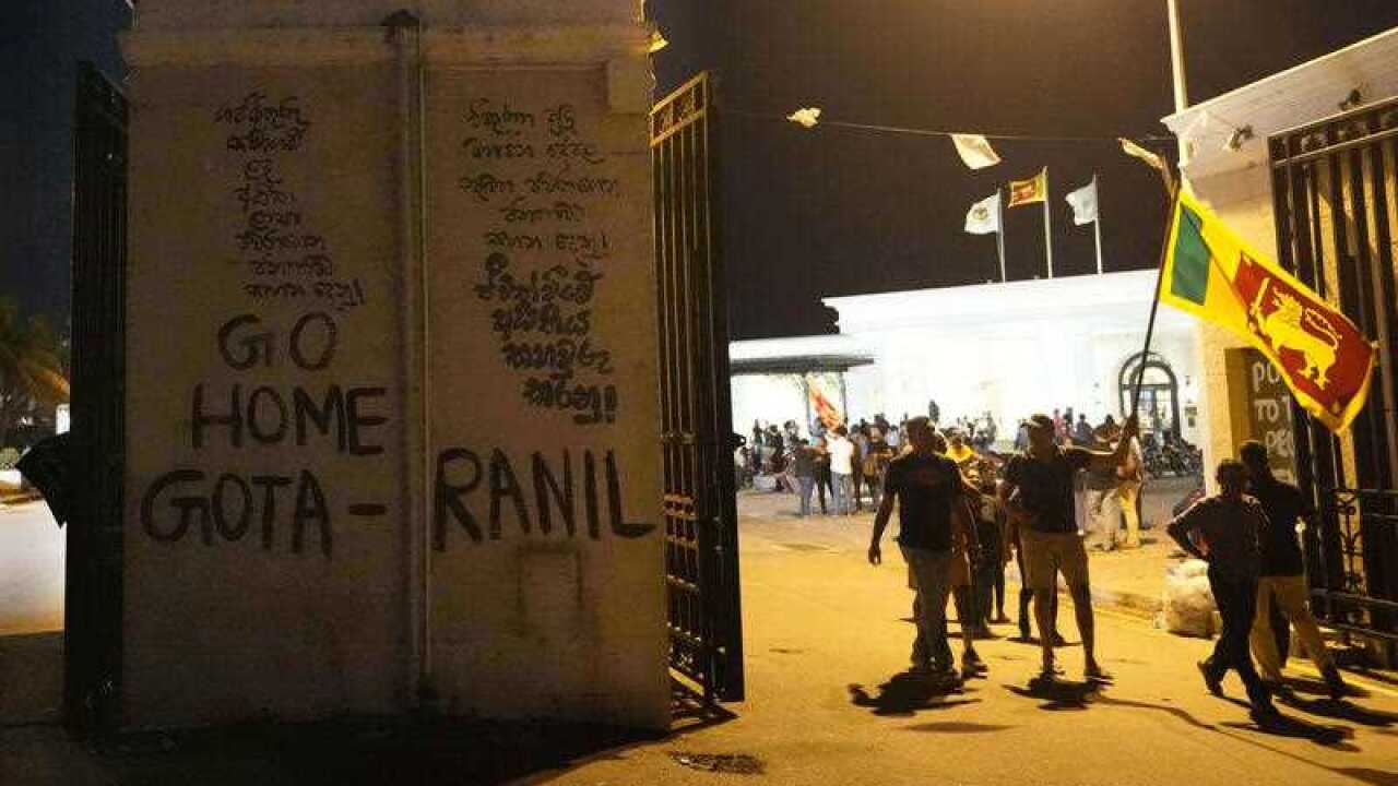 Protesters walk past a vandalised security gate at the entrance to president's official residence in Colombo, Sri Lanka, Saturday, July 9, 2022.
