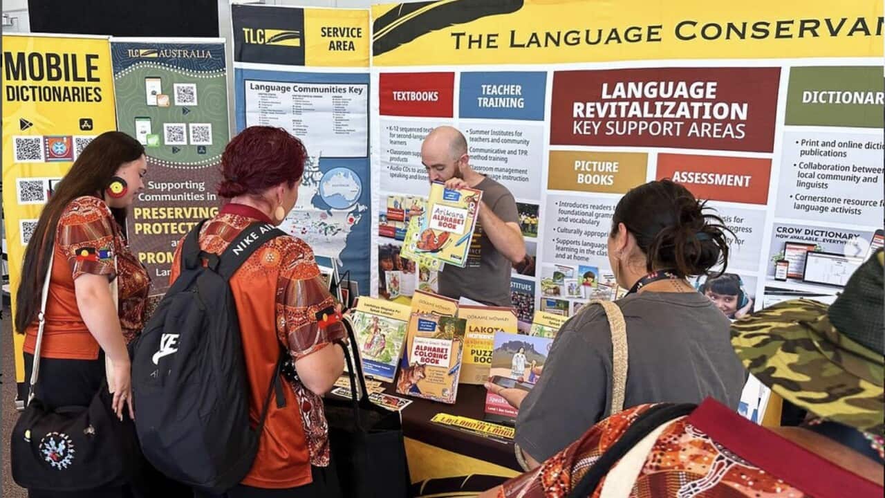 Attendees gather around a table with books on Indigenous languages.