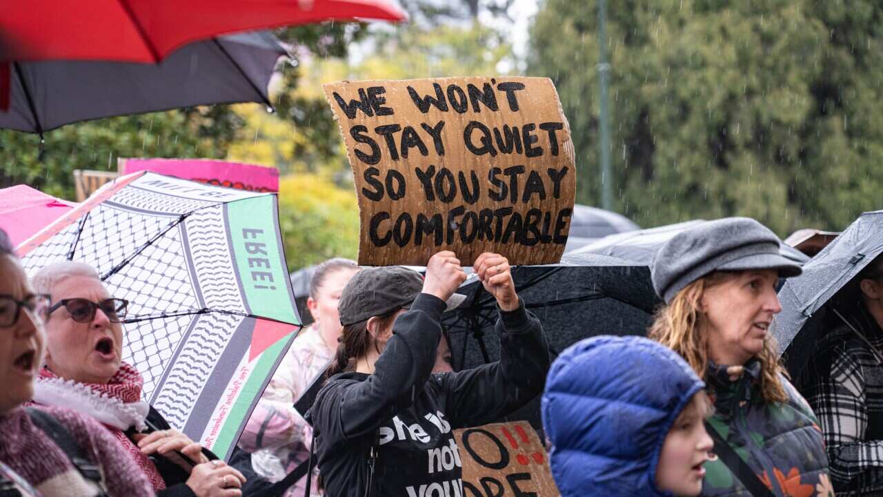 A protester holds a placard that says " We wont stay quiet