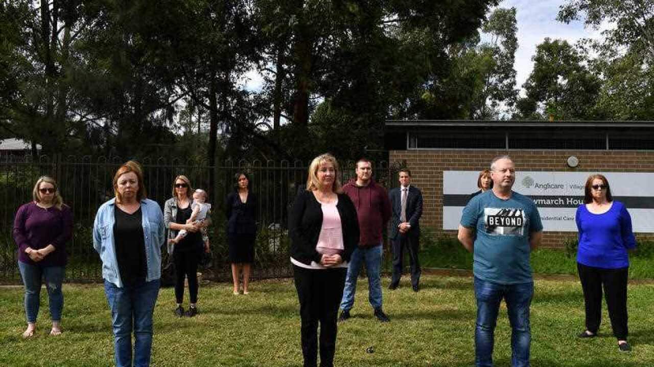 Family members of residents of Anglicare's Newmarch House practice social distancing as they stand outside the aged care home in Kingswood, near Penrith.