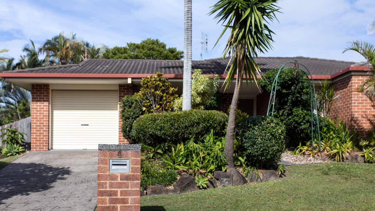 A brick home, with a bit of grass and greenery, a single car garage and a number 4 on the letterbox.