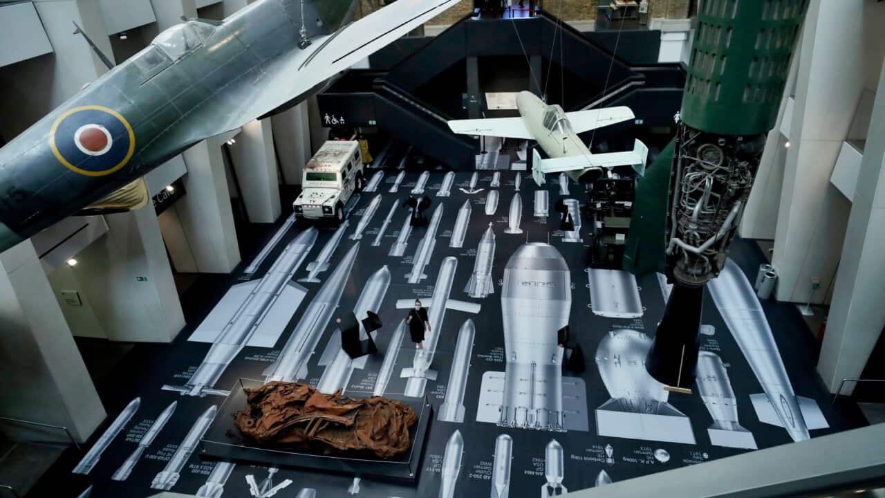 A staff member poses for photographs as the new commission by Chinese artist Ai Weiwei entitled "History of Bombs" which covers the floor and a staircase is showcased in the Atrium at the Imperial War Museum in London, Wednesday, July 29, 2020. The museum