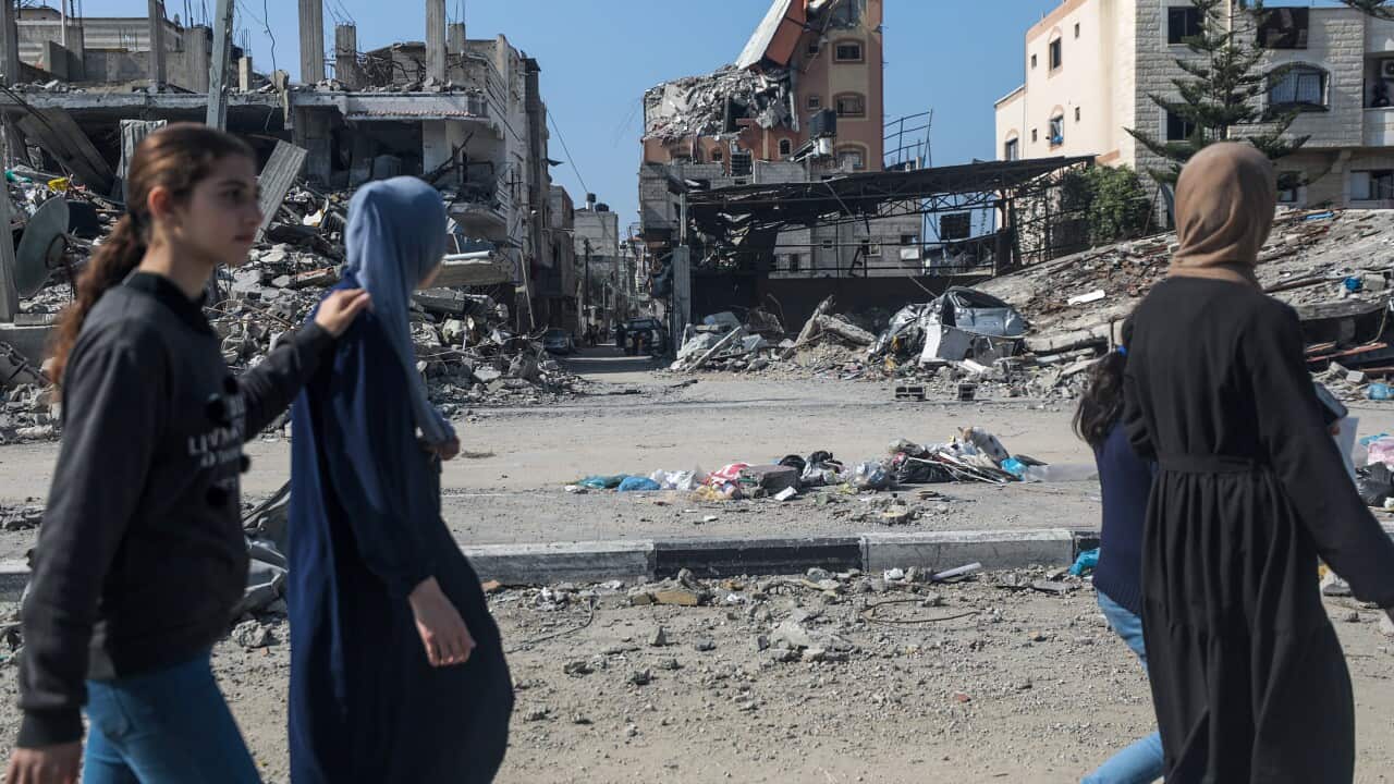 Palestinians walk past destroyed residential buildings in Al Nuseirat refugee camp, central Gaza Strip.