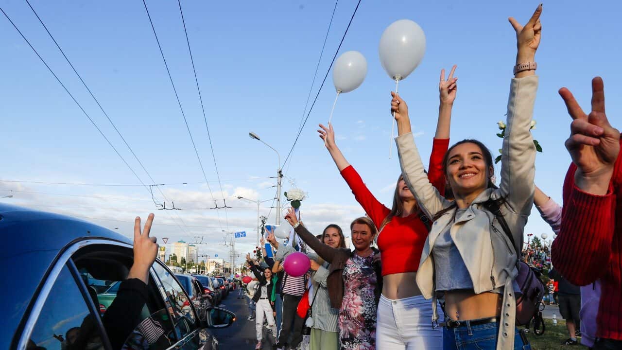 People greet each other waving flowers and balloons as they protest in the Belarus capital on 13 August.