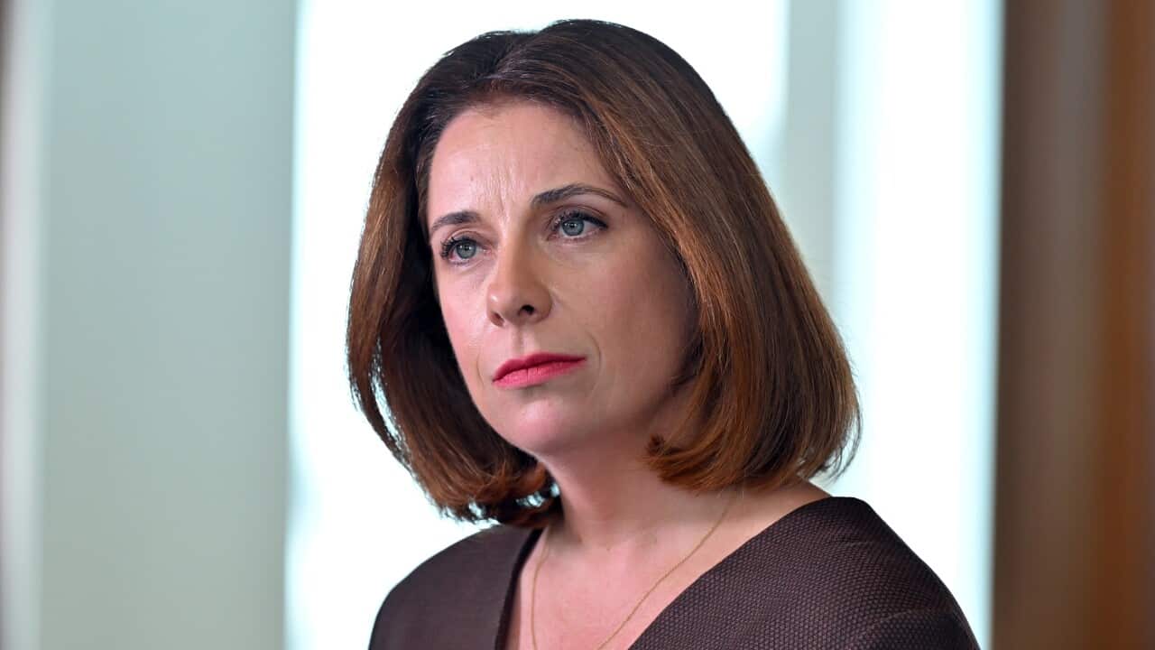 A woman with medium-length, warm brown hair is looking slightly off-camera, her expression serious.
