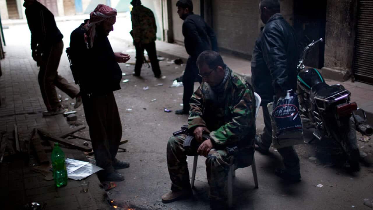 Syrian rebels pause for a moment in between fierce fire fights with the Syrian Army in the town of Idlib, north Syria. (AAP)