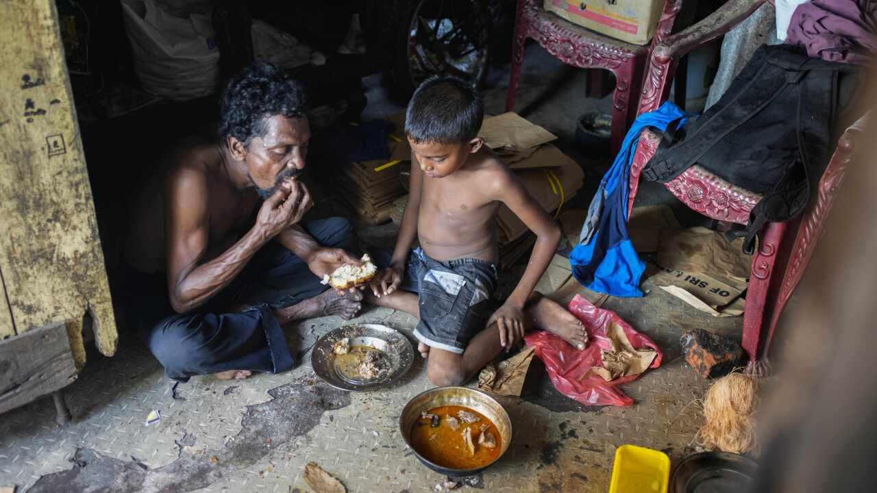 Man and son eating off a pan on the ground.