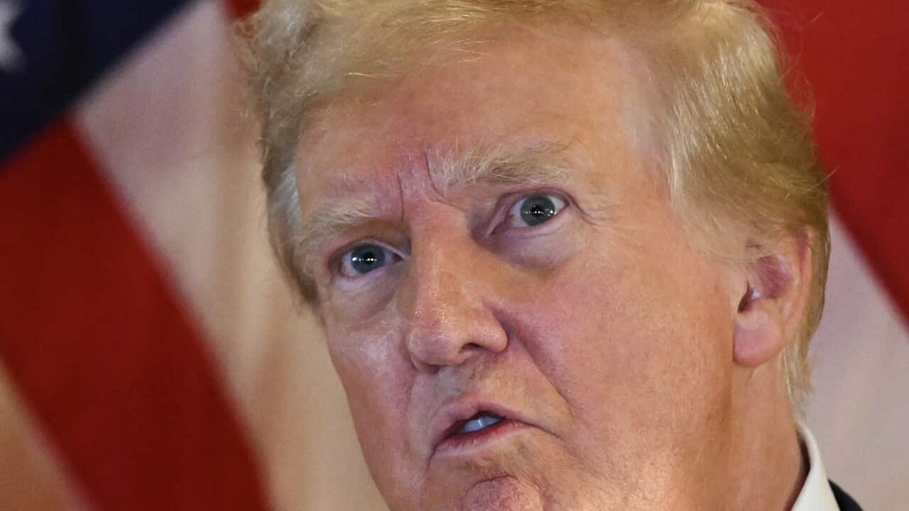 Donald Trump speaks during a press conference with the US flag in the background.