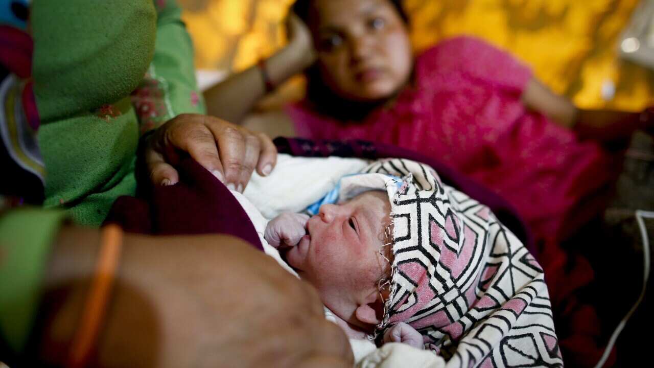 A newborn is held by her aunt as her mother rests in the background at a makeshift hospital in Bhaktapur, Kathmandu, Nepal, 29 April 2015. (EPA/DIEGO AZUBEL)