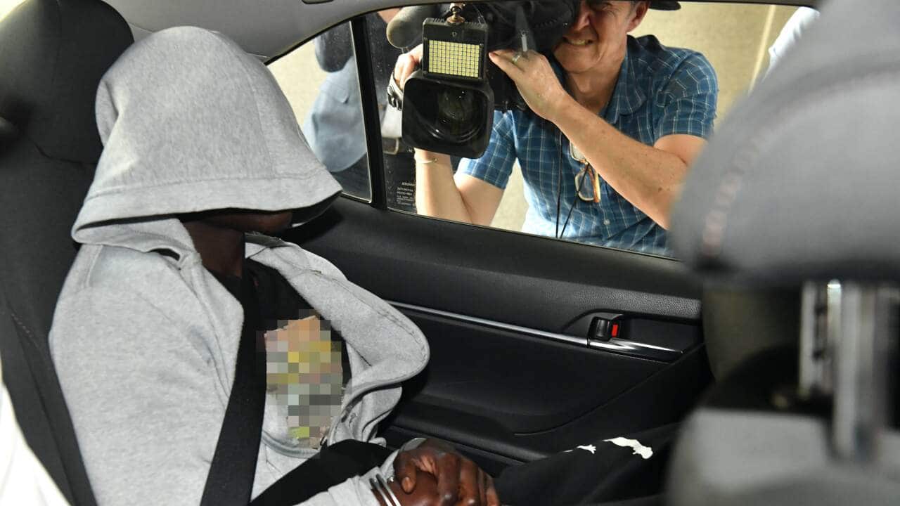 A man is seen being driven into the Brisbane Watchhouse by police.