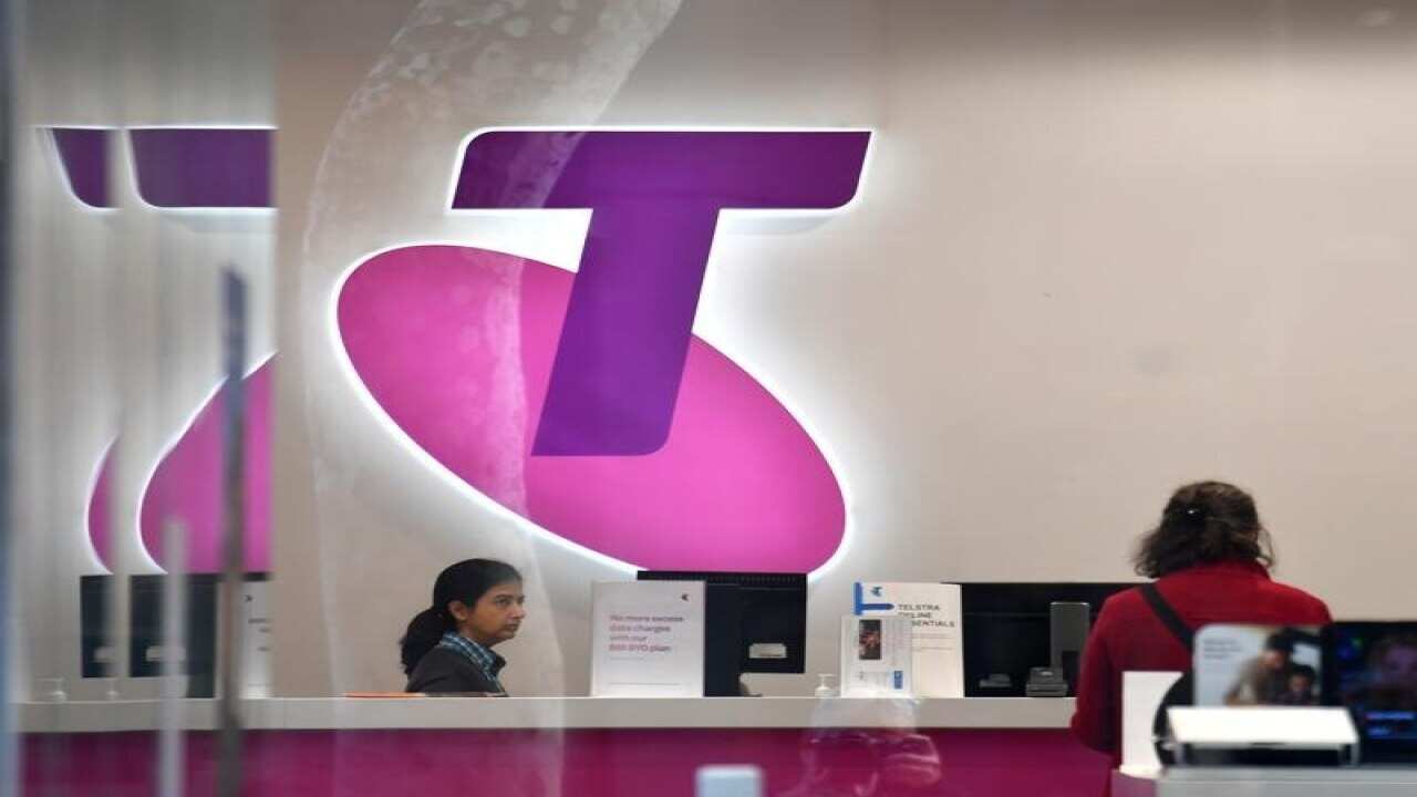 Customers and assistants are seen in a Telstra store.