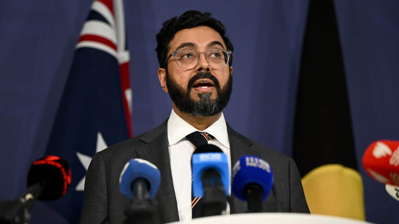 A man speaking into microphones at a press conference.