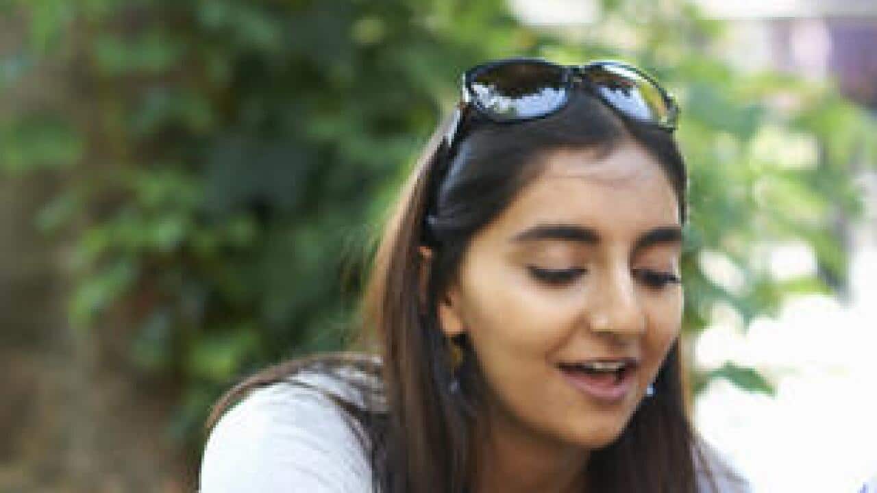 Male and female students sitting chatting and working on college campus