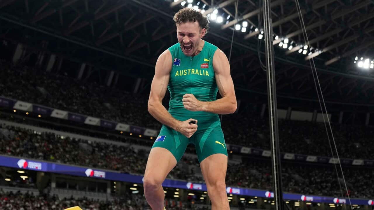 A man in a green athletics one-piece outfit with Australia written in gold lettering on the front celebrates