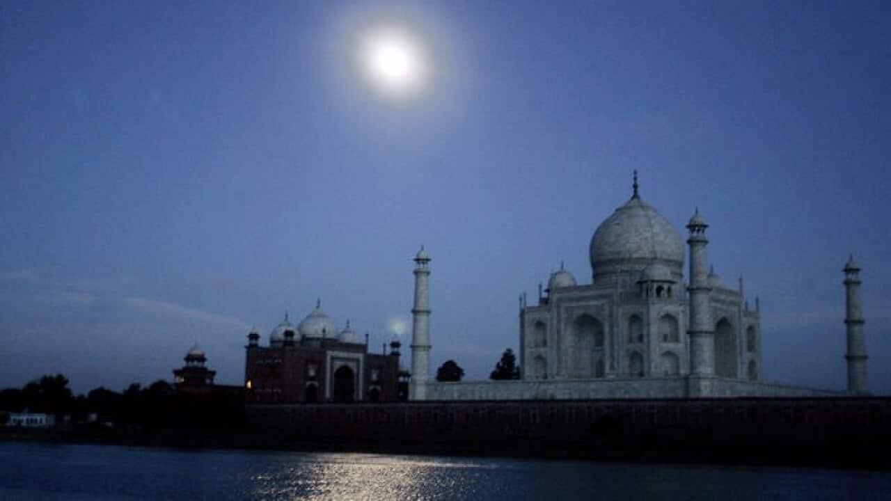 The moon is reflected in the River Yamuna as it flows past the Taj Mahal in Agra