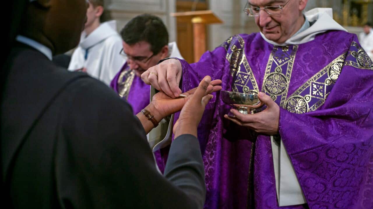 Churchgoers receive holy communion into their hands during a Mass celebrated at St Francois Xavier church in Paris