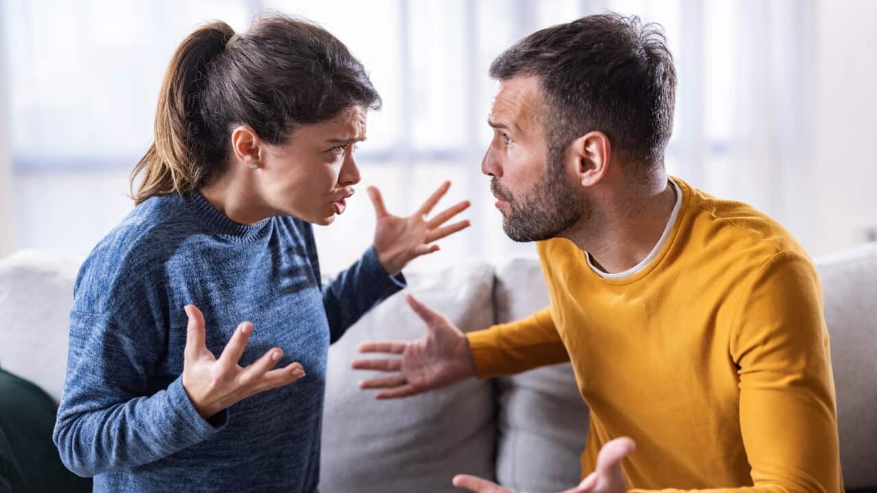 Mid adult couple arguing on sofa at home.