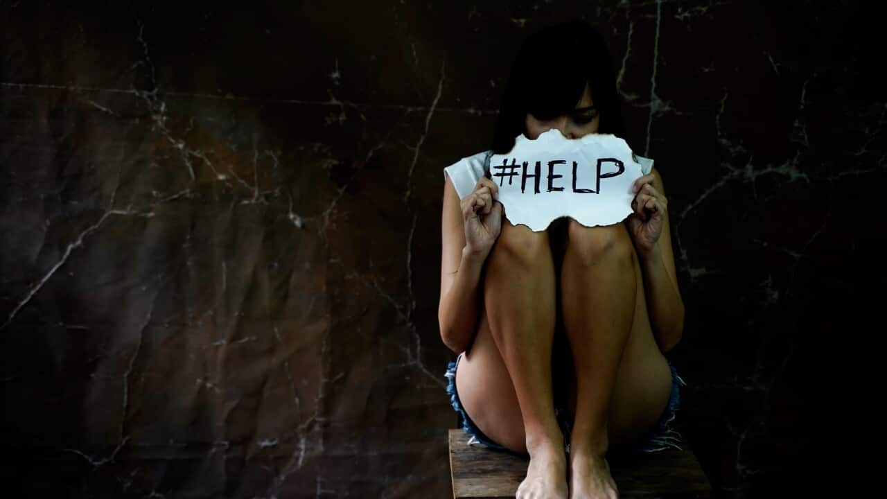 Woman sitting on chair and holding a plaque with the inscription about the help. Inscription against domestic violence.