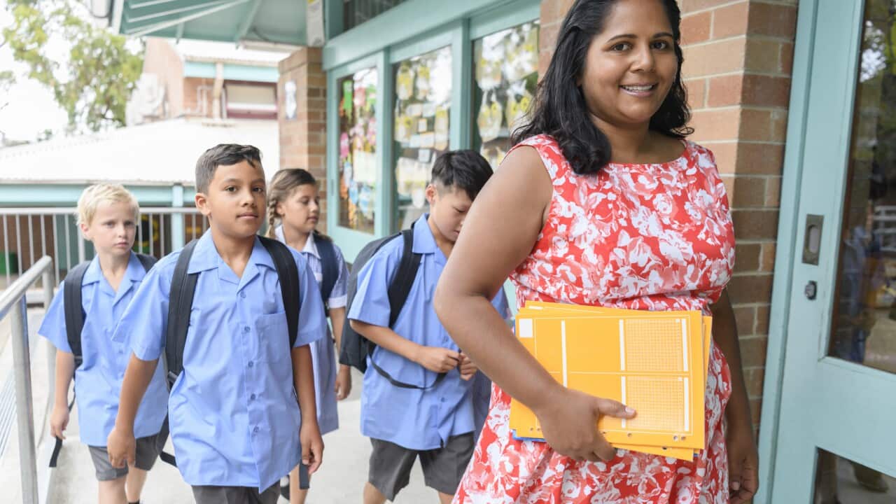 School teacher and pupils arriving at school