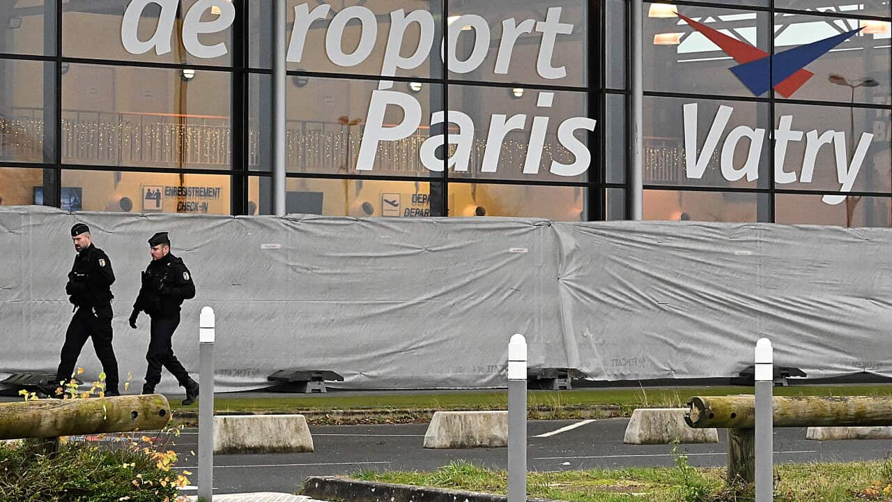 Two gendarmes patrol around a terminal at an airport.