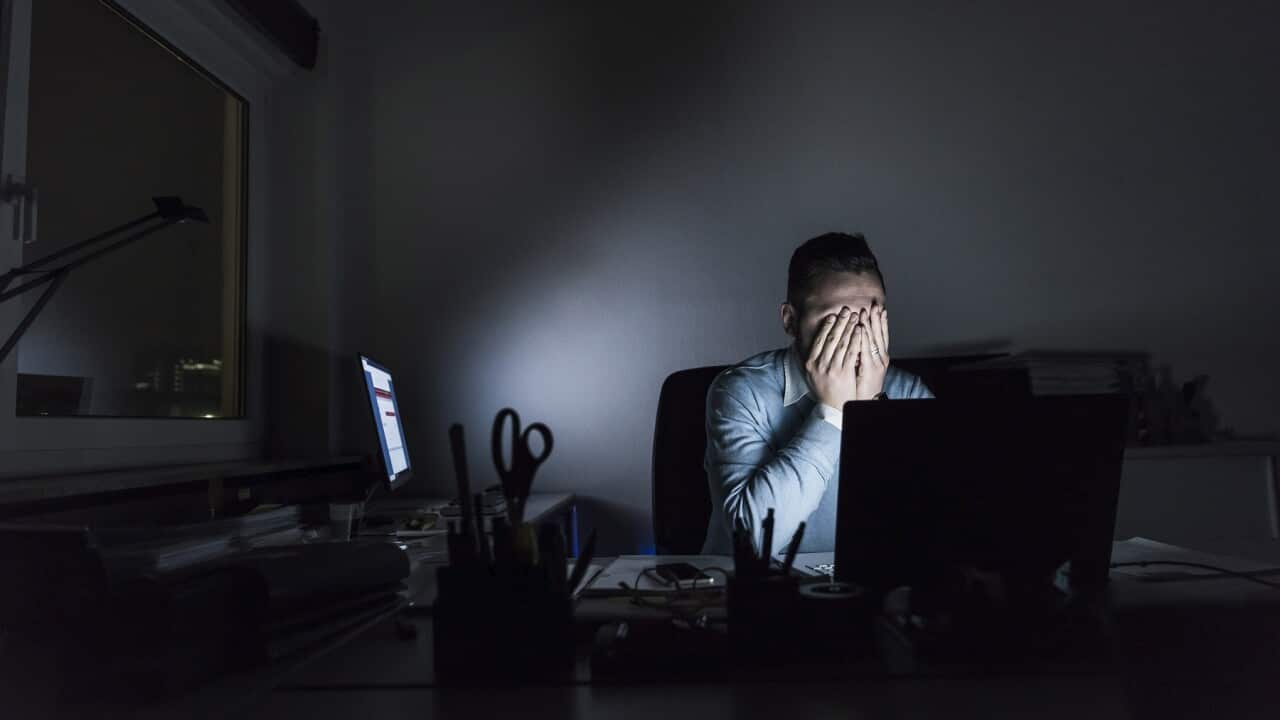 Exhausted businessman sitting at desk in office at night