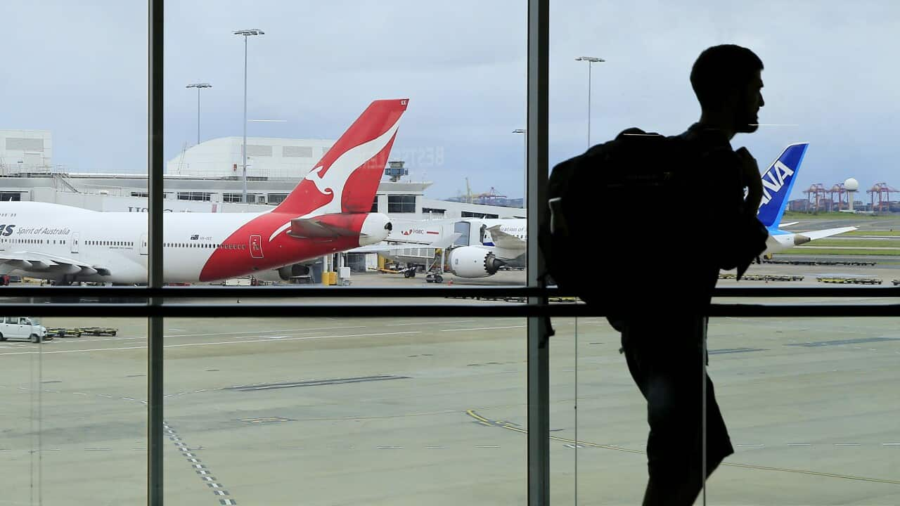 A man walking past a window at an airport. There are planes parked outside.