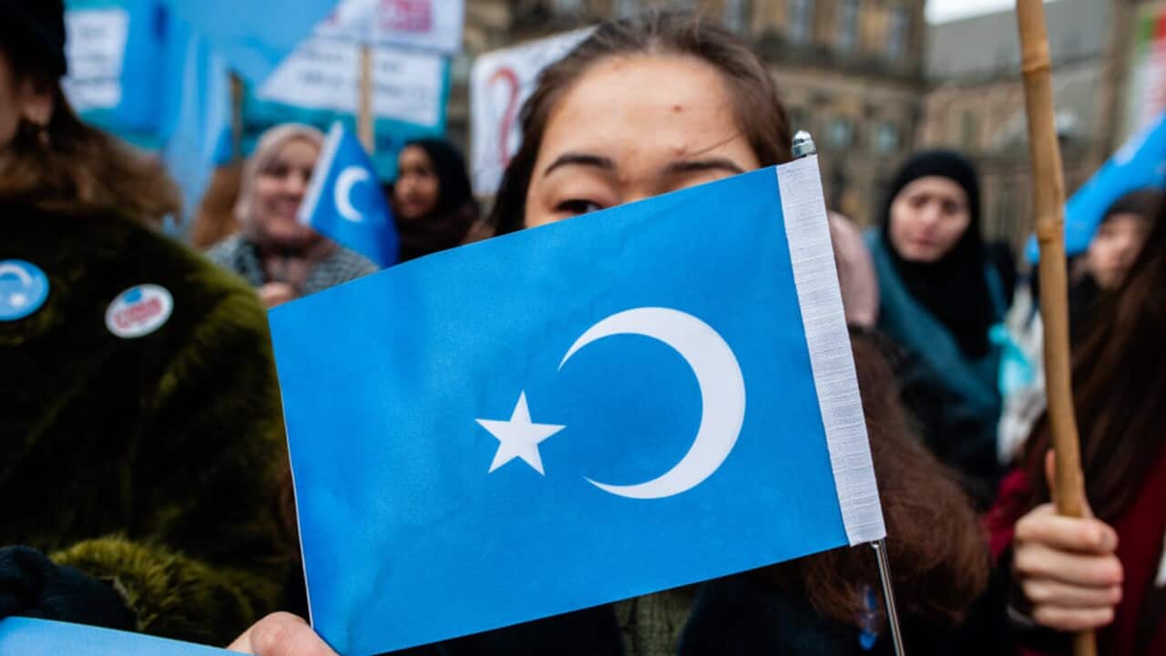 A woman holds a flag at a demonstration in support of Uighurs