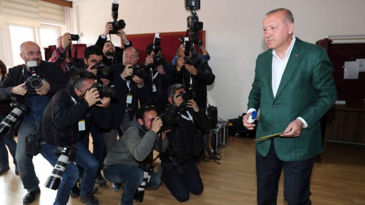 Turkey's President Recep Tayyip Erdogan, walks to cast his ballot during the local elections