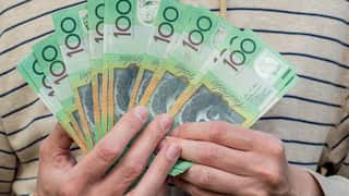 A person holding Australian $100 banknotes