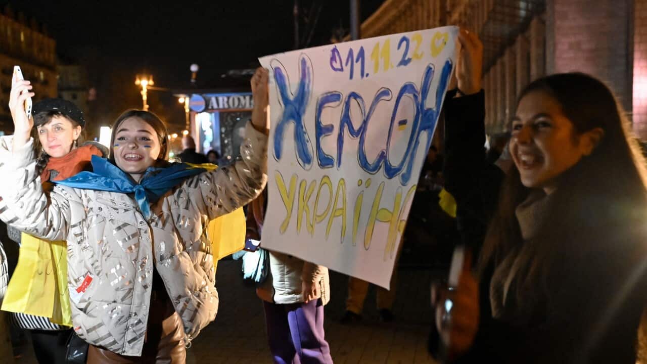 Ukrainians hold signs celebrating the recapture of Kherson by Ukrainian troops.
