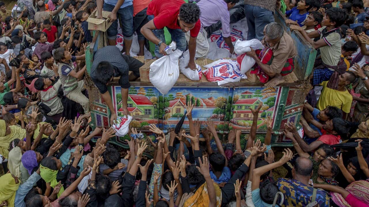 Rohingya Muslims, who crossed over from Myanmar into Bangladesh, stretch their arms out to collect food items distributed by aid agencies.