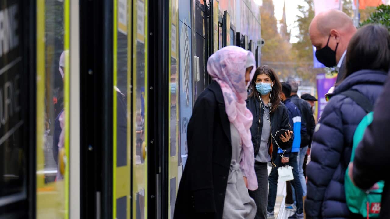 Two women exit a tram, while others wait to enter.