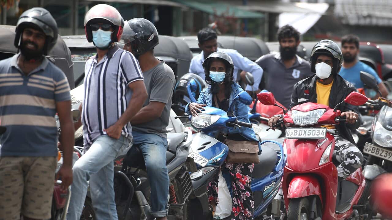 People on motorbikes queuing at a petrol station.