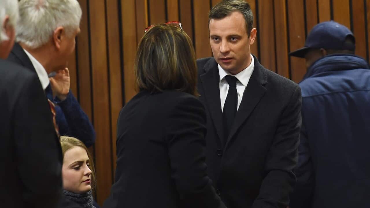 Paralympic gold medalist Oscar Pistorius talks to family members in court on July 6