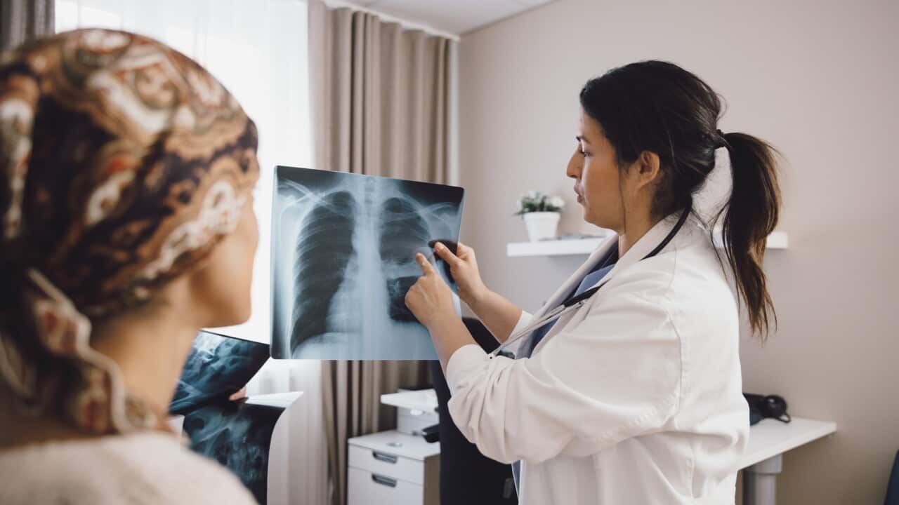Hispanic female expertise giving advice to cancer patient while examining x-ray at doctor's office