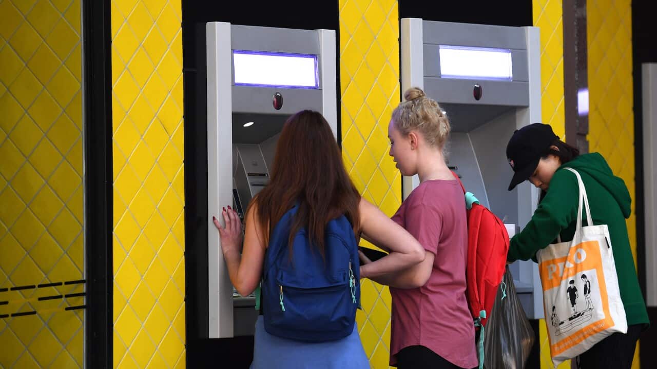 People standing in front of Commonwealth Bank ATMs withdrawing cash