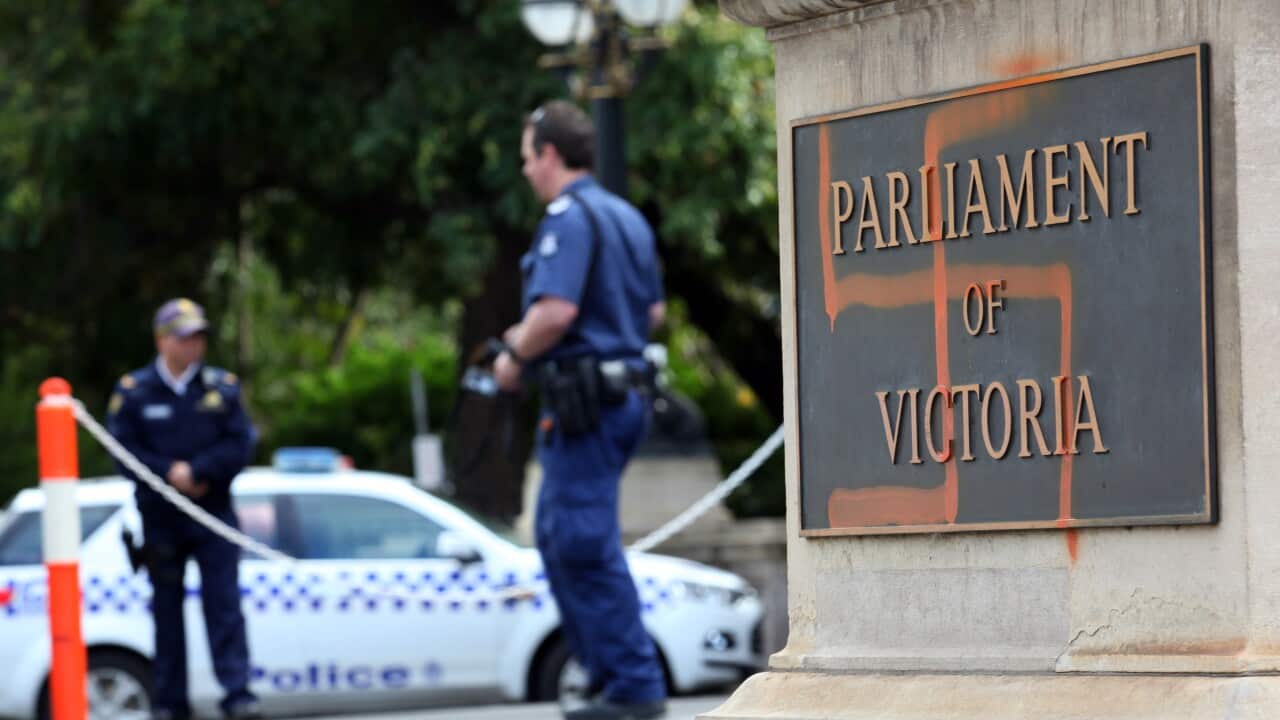 Police inspect graffiti on the front of the Victorian state parliament