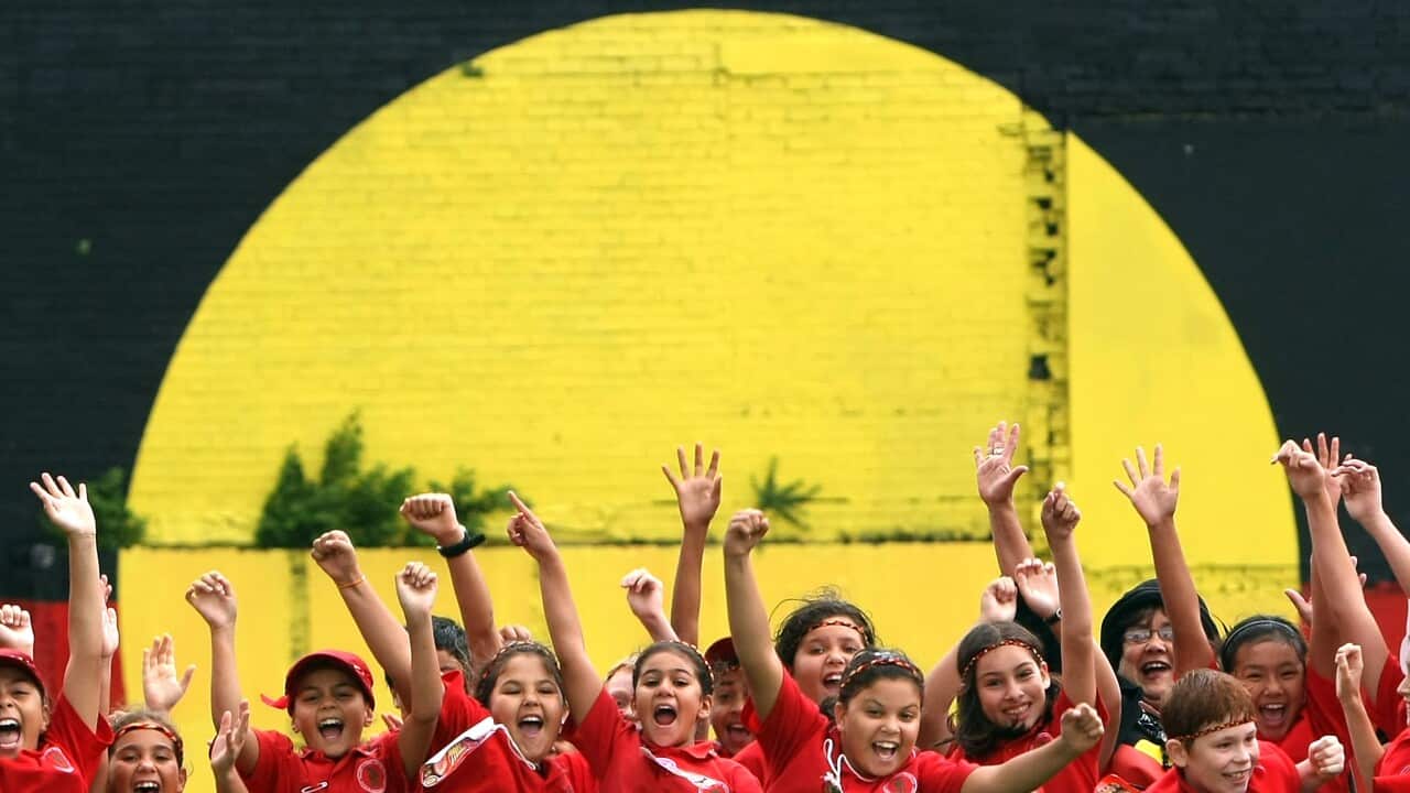 Indigenous children at in front of a mural