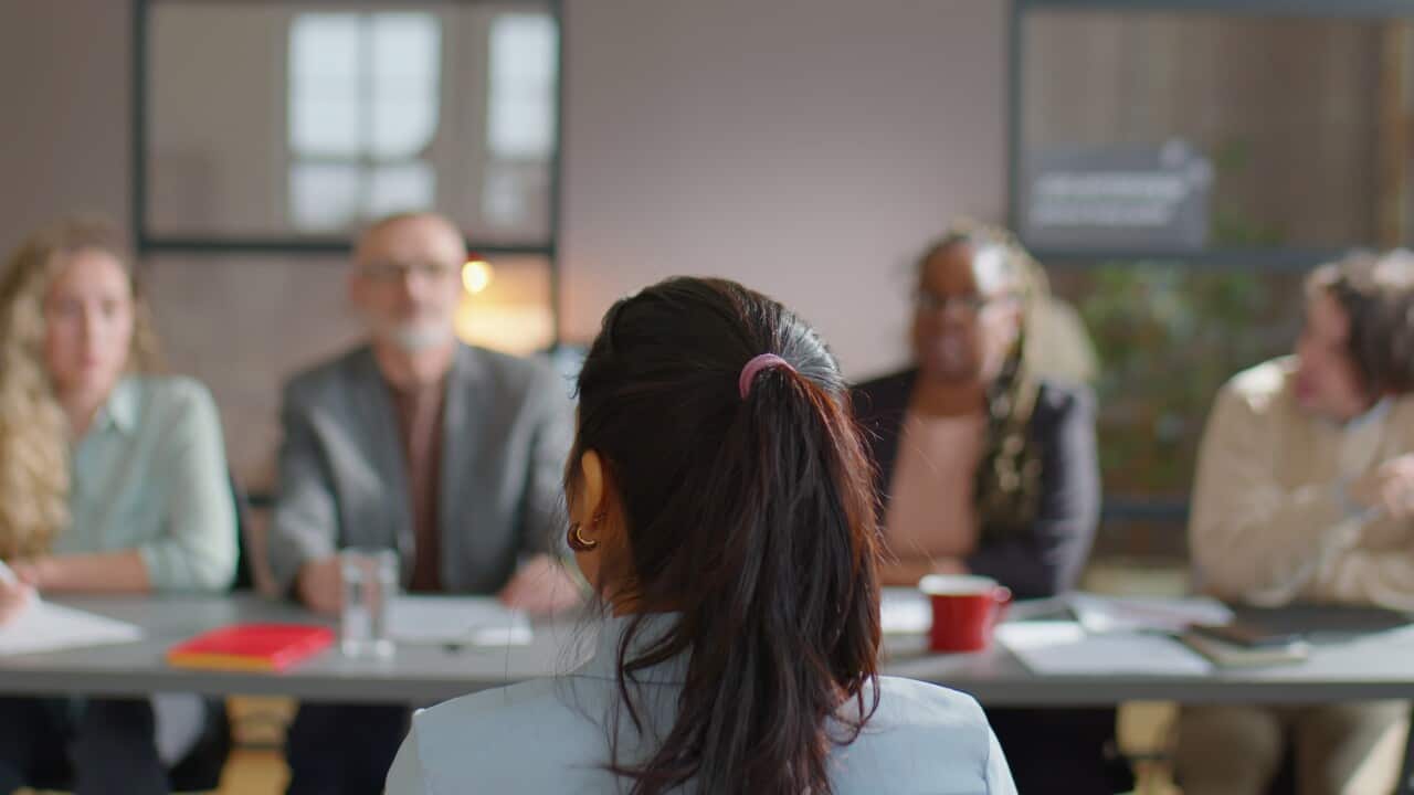 rack-focus-shot-of-woman-sitting-in-front-of-hiring-committee-of-multiethnic-hr-manage-SBI-350599385.jpg