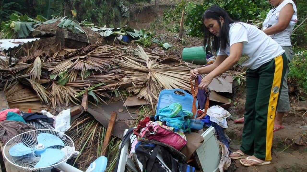 Filipinos at a landslide-damaged home