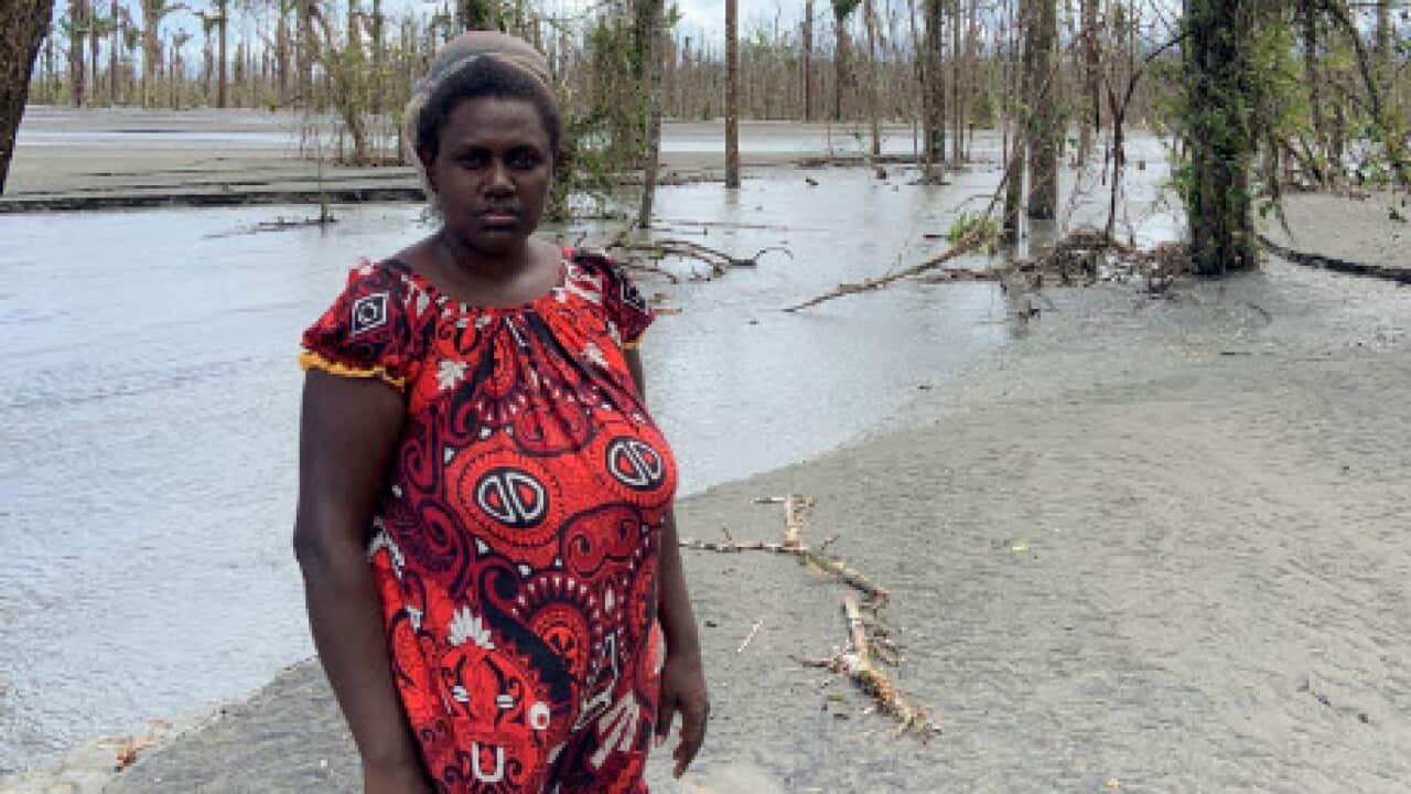 Theonila Roka Matbob standing in front of an area destroyed by mine waste flooding. 