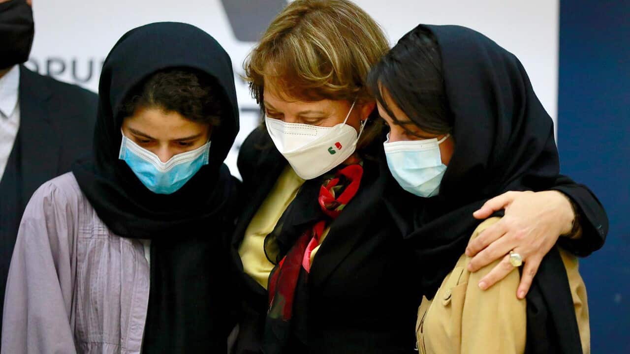 Mexican minister Martha Delgado (C) hugs two Afghan refugees part of an all-girls robotics team 