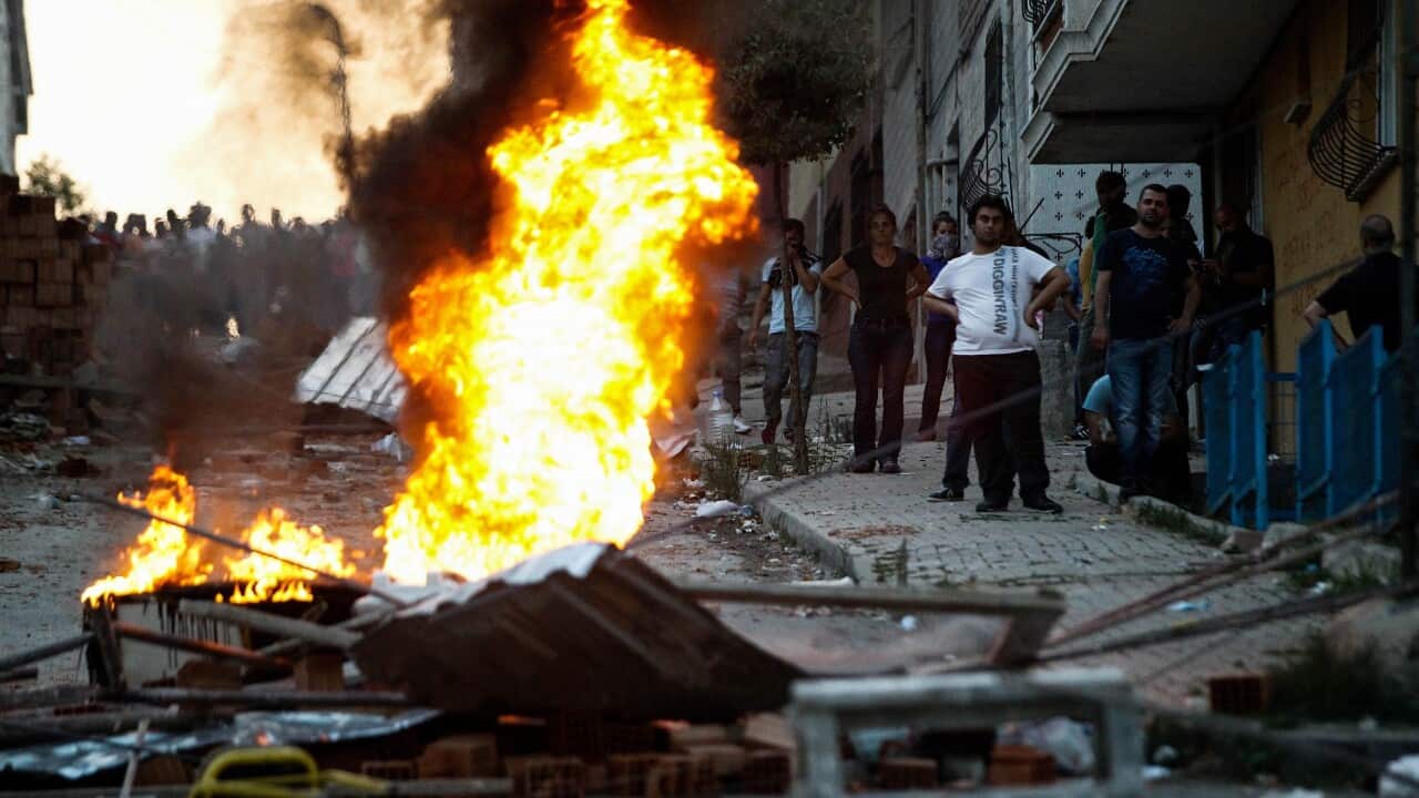 Protesters stand behind a burning barricade during clashes with Turkish riot police in the Gazi district of Istanbul, Turkey, 26 July 2015.