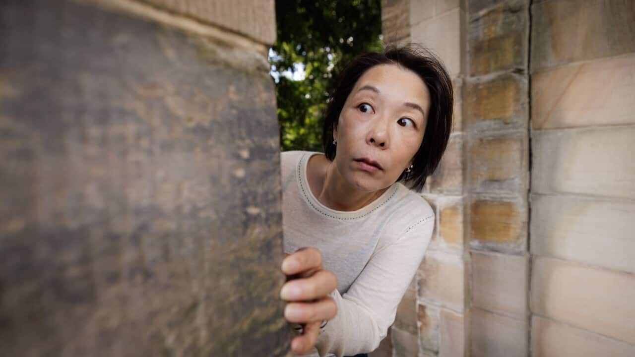 Scared woman looking around a corner
